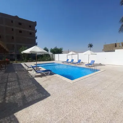 a swimming pool with lounge chairs and umbrellas at El Fayrouz Villa in Luxor