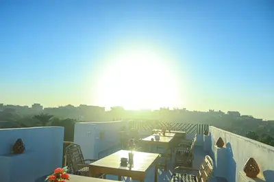 a rooftop patio with tables and chairs and the sun at Holiday Dream Of Luxor in Luxor