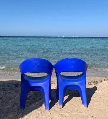 two blue plastic chairs sitting on the beach at Hurghada mit Charme in Hurghada