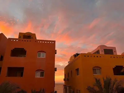 two buildings with a sunset in the background at Home from Home Al Dora Residence in Hurghada