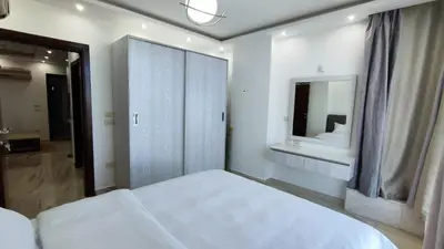 a white bedroom with a bed and a mirror at Stylish Sunny Central 1BR Apartment Hurghada in Hurghada