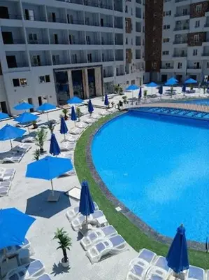 a large pool with chairs and blue umbrellas at Tiba Golden Down Town in Hurghada