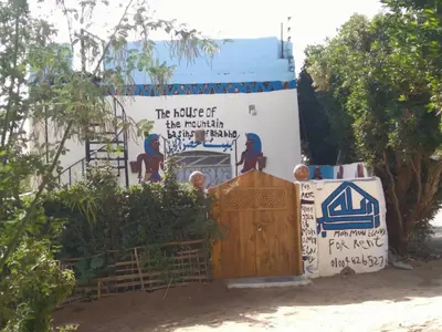 a sign in front of a building with a wooden door at Mountain hug house in Luxor