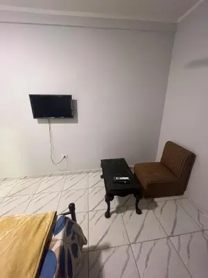 a room with a chair and a tv on a wall at Cozy Studio on Sheraton Road near Metro Market in Hurghada