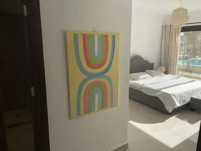 a painting of a rainbow on a wall next to a bed at GCribs in Hurghada