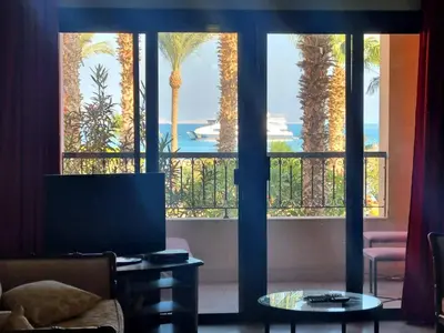a living room with a large window with palm trees at Esplanadа Apartments in Hurghada