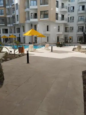 a patio with chairs and umbrellas in front of a building at Studiowohnung Aqua Infinity in Hurghada