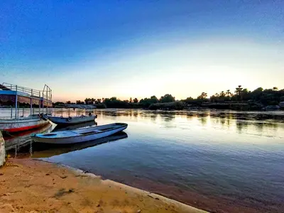 two boats are docked on the shore of a river at Fox Nubian Hotel in Aswan