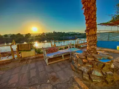 a patio with a bed and a tree at sunset at Fox Nubian Hotel in Aswan