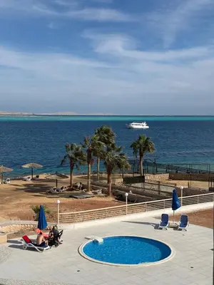 a swimming pool next to the ocean with a cruise ship at Studio By The Beach in Hurghada
