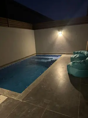 a large swimming pool with chairs in a room at night at 2 BR with a small private pool in Hurghada