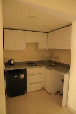 a kitchen with white cabinets and a black dishwasher at Kinga Apartment Florenza Khamsin in Hurghada