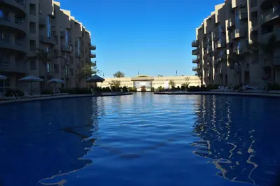 a pool of water in front of some apartment buildings at Hurghada Princess resort, Private Sandy Beach & 3 Pools in Hurghada
