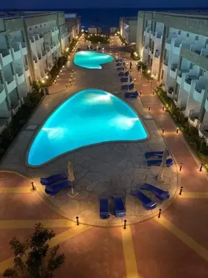 an overhead view of a large swimming pool at night at Lovely APT Sunny Beach Front, Near Senzo Mall Free WIFI in Hurghada