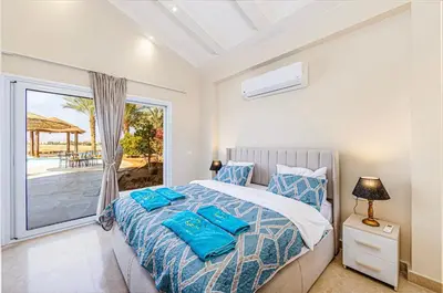 a bedroom with a bed with blue pillows on it at Stunning villa with private heatable pool in Hurghada