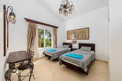 a bedroom with two beds and a table and a chandelier at Stunning villa with private heatable pool in Hurghada