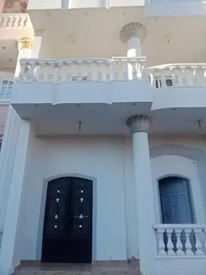 a white building with a black door and a balcony at elomda in Luxor
