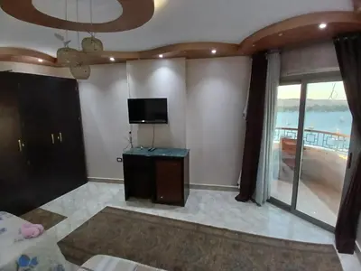 a living room with a television and a balcony at Monty Homestay in Aswan