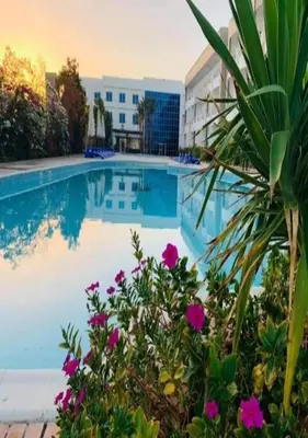 a swimming pool with purple flowers in front of a building at Furnished Chalets for Rent in Cecilia Resort Furnteched, kitchenee, Near Airport in Hurghada