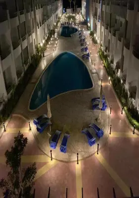 a pool in the middle of a building with blue chairs at Furnished Chalets for Rent in Cecilia Resort Furnteched, kitchenee, Near Airport in Hurghada