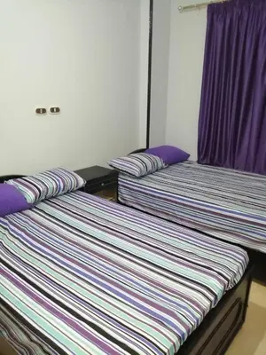 two beds in a room with purple curtains at Al Dahar apartments Hurghada in Hurghada