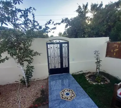 a black door in a white wall with a plant at Upper Egypt House in Luxor