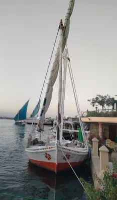 a sail boat tied to a dock in the water at Nile House Anis & Do in Luxor