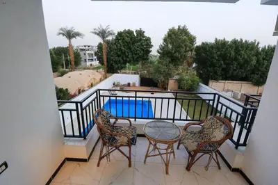 a balcony with a table and chairs and a pool at Villa Abo Tarek in Al Aqālitah