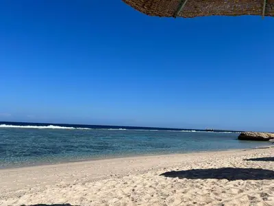 a beach with a straw umbrella and the ocean at Villa Shams El Bahr in Hurghada