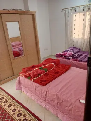 a bedroom with two beds with pink sheets and a mirror at Eslam apartment 2 in Hurghada