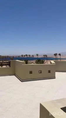 a building with a view of the ocean and palm trees at Exklusives Apartment mit Dachterrasse und Meerblick in Hurghada