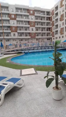 a pool with a chair and a palm tree next to a building at Tiba Golden Resort in Hurghada