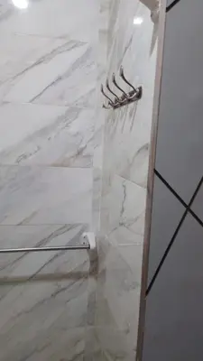 a bathroom with a shower with a white marble wall at Tiba Golden Resort in Hurghada