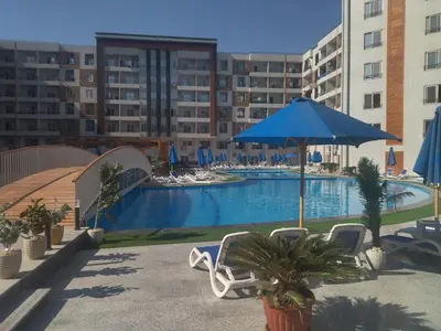 a swimming pool with a blue umbrella and chairs and a hotel at Tiba Golden Resort apartment 167 in Hurghada