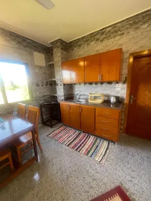 a kitchen with wooden cabinets and a table and a dining room at Tonys Flat in Al Aqālitah
