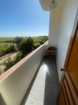 a room with a balcony with a chair and a window at Tonys Flat in Al Aqālitah