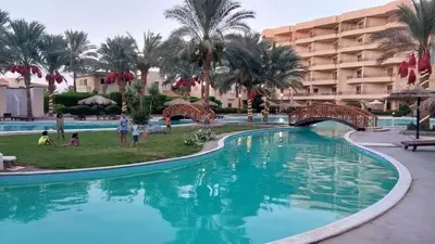 a large swimming pool in a resort with a bridge at Home always in Hurghada