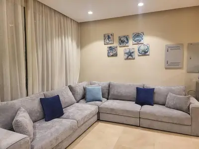 a living room with a gray couch with blue pillows at Mangroovy 1 br Ground Composure & Cool Hilton view in Hurghada