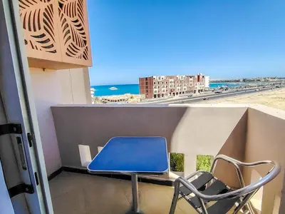 a blue laptop sitting on a balcony with a chair at Sea view one bedroom apartment in Hurghada Dreams in Hurghada