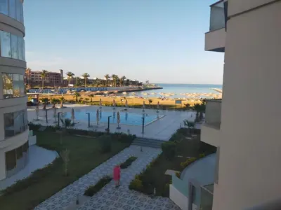 a person standing next to a beach with umbrellas at Scandic resort hurghada in Hurghada