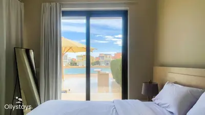 a bedroom with a bed and a view of a pool at Ollystays Tawila 3BR Townhouse Shared Pool in Hurghada