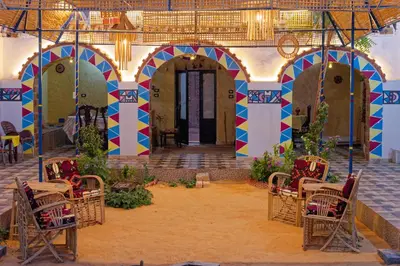 a building with colorful arches and tables and chairs at Nuba life hostel in Najâ€˜ al MadÄbb