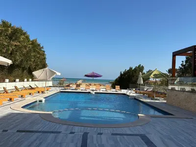 a swimming pool with chairs and umbrellas at a resort at البلكان بيتش ريزورت Balkan Beach Resor in Hurghada