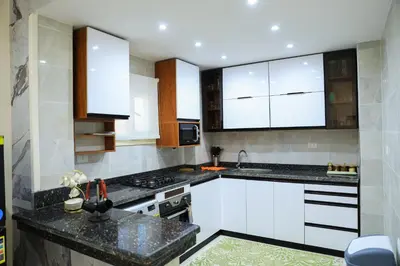 a kitchen with white cabinets and black counter tops at Peaceful Magawish Apartment in Hurghada