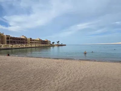 a beach with people in the water and buildings at Taiba Golden Central Hurghada in Hurghada