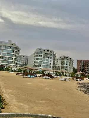 a sandy beach with tall buildings in the background at Scandic Resort Hurghada in Hurghada
