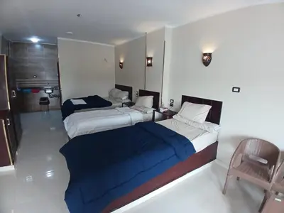 a hotel room with two beds and a chair at Nile Moon in Jazīrat Aswān