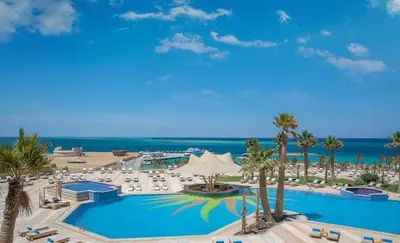 a resort with a large swimming pool with palm trees and chairs at Hurghada in Hurghada