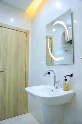 a white bathroom with a sink and a mirror at Peaceful Magawish Apartment in Hurghada