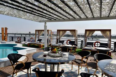 a patio with tables and chairs and a pool at King of The Vally Nile Cruise Aswan To Luxor 3 Night And visit the Nubian village in Aswan